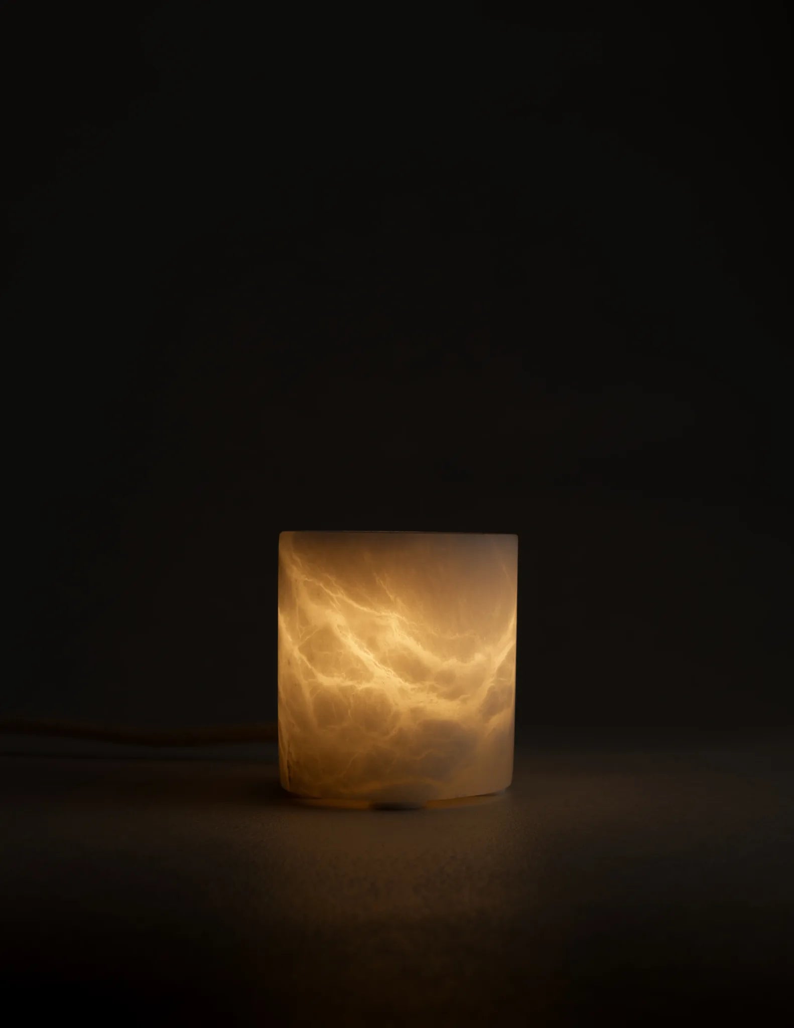 Lámpara de alabastro BARLET encendida, con vetas iluminadas sobre fondo oscuro.